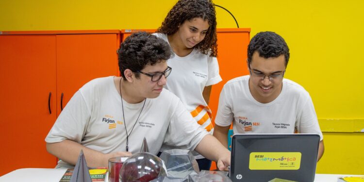 Imagem ilustrativa: estudantes com camisetas da Firjan Senai usam notebook em sala de aula, sobre cursos técnicos gratuitos