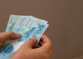 Mãos segurando notas de dinheiro em referência às formas flexíveis de gerar renda para estudantes em 2026.