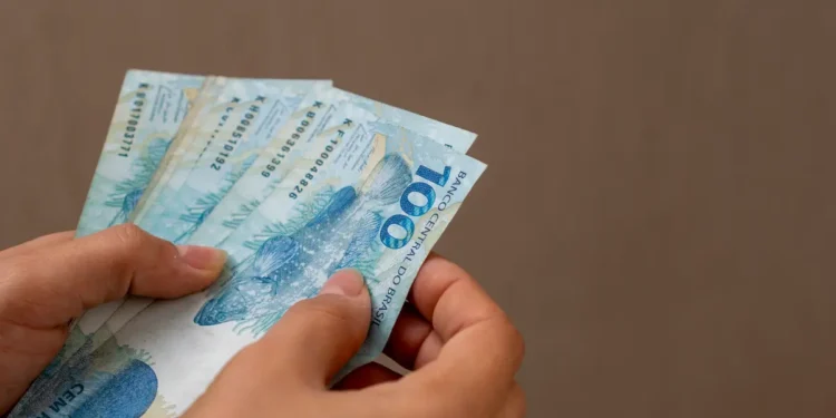 Mãos segurando notas de dinheiro em referência às formas flexíveis de gerar renda para estudantes em 2026.
