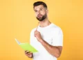 Homem estudando português com caderno representa a dúvida sobre a expressão "há dez mil anos atrás" e as regras da gramática.