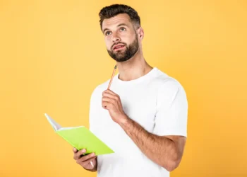 Homem estudando português com caderno representa a dúvida sobre a expressão "há dez mil anos atrás" e as regras da gramática.