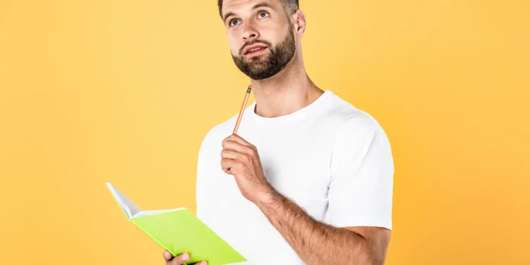 Homem estudando português com caderno representa a dúvida sobre a expressão "há dez mil anos atrás" e as regras da gramática.
