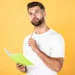 Homem estudando português com caderno representa a dúvida sobre a expressão "há dez mil anos atrás" e as regras da gramática.