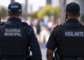 Guarda municipal e vigilante fardados de costas, representando a comparação entre salários, requisitos, estabilidade e benefícios das duas carreiras de segurança em 2026.