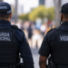 Guarda municipal e vigilante fardados de costas, representando a comparação entre salários, requisitos, estabilidade e benefícios das duas carreiras de segurança em 2026.