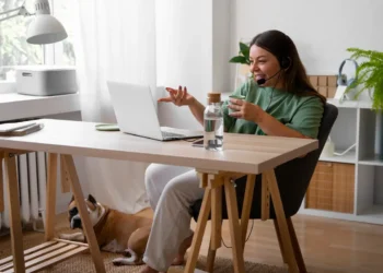 Profissional trabalha em home office com notebook e headset enquanto participa de atendimento online.