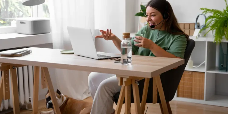Profissional trabalha em home office com notebook e headset enquanto participa de atendimento online.