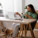 Profissional trabalha em home office com notebook e headset enquanto participa de atendimento online.