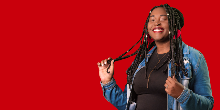 Jovem sorridente de jaqueta jeans posando sobre fundo vermelho, na identidade visual usada na divulgação do programa jovem aprendiz do iFood.