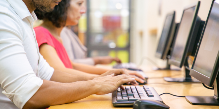 Profissionais utilizam computadores em ambiente de trabalho para realizar tarefas de informática.