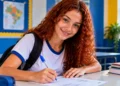 Jovem estudante preenchendo formulário em ambiente escolar representa oportunidade de Jovem Aprendiz.