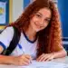 Jovem estudante preenchendo formulário em ambiente escolar representa oportunidade de Jovem Aprendiz.