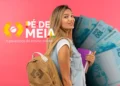 Jovem estudante com mochila e cadernos à frente de notas de cem reais e logo Pé-de-Meia, simbolizando os quatro pagamentos que ainda serão liberados pelo programa em 2026.
