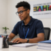 Jovem estagiário trabalhando em escritório da Secretaria da Administração do Estado da Bahia, simbolizando as vagas do Partiu Estágio.
