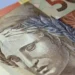 Notas de dinheiro brasileiro representando o pagamento mensal de R$ 700 do Pé-de-Meia Licenciaturas.