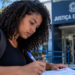 Pessoa preenche documento em frente a unidade da Justiça Eleitoral.