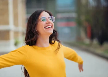 Mulher sorrindo ao ar livre representa resiliência mental e equilíbrio emocional.