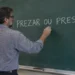 Professor escrevendo as palavras “prezar ou presar” no quadro durante aula de língua portuguesa.