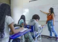 Professora aplicando aula em sala de ensino com alunos durante atividade escolar.