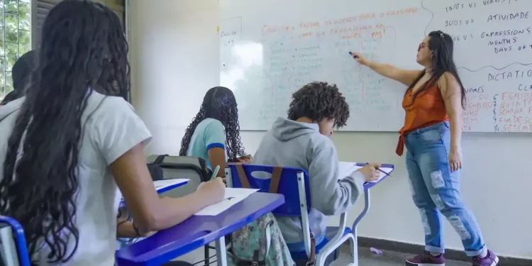 Professora aplicando aula em sala de ensino com alunos durante atividade escolar.