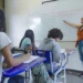 Professora aplicando aula em sala de ensino com alunos durante atividade escolar.
