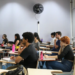 Estudantes sentados em carteiras de uma sala de aula, com cadernos e garrafas de água sobre as mesas, acompanhando a aula durante a preparação para o Provão Paulista.