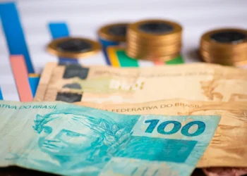 Cédulas de dinheiro brasileiro e moedas representam as diferenças entre salário mínimo, piso salarial e salário normativo.