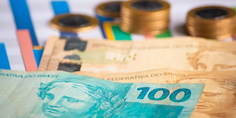 Cédulas de dinheiro brasileiro e moedas representam as diferenças entre salário mínimo, piso salarial e salário normativo.