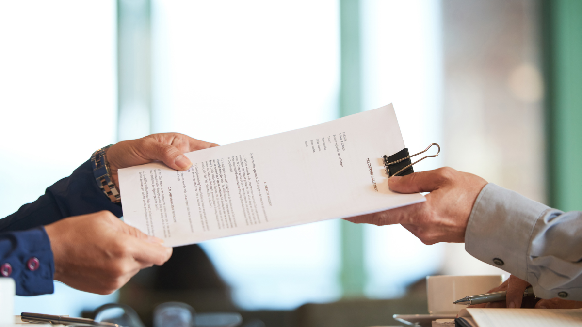 Pessoas assinando documento de rescisão de contrato de trabalho em ambiente profissional.