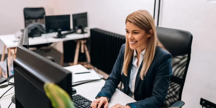 Profissional de secretariado trabalhando em computador em ambiente de escritório.