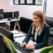 Profissional de secretariado trabalhando em computador em ambiente de escritório.