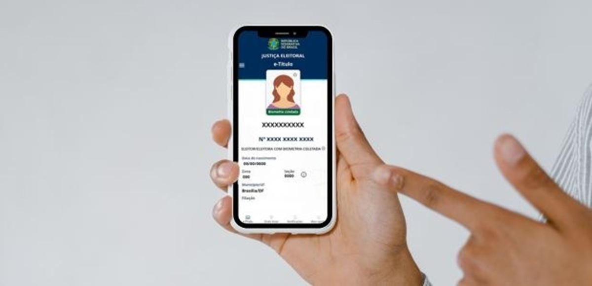 Imagem ilustrativa: mãos segurando um celular com a tela do e-Título aberta, exibindo os dados do eleitor na Justiça Eleitoral