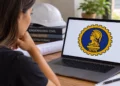 Mulher observa no computador símbolo da Engenharia formado por Minerva e uma engrenagem.