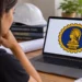 Mulher observa no computador símbolo da Engenharia formado por Minerva e uma engrenagem.