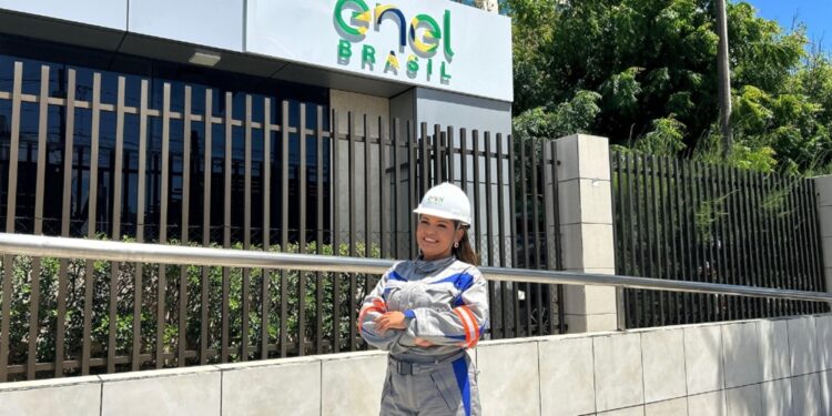 Imagem ilustrativa: profissional de uniforme e capacete em frente à sede da Enel Brasil, sobre as vagas para eletricistas