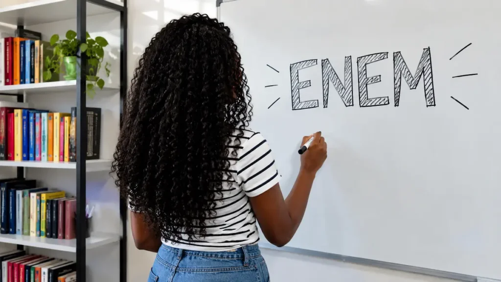 Jovem escrevendo o nome Enem em quadro branco.
