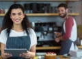 Barista sorridente com tablet em cafeteria moderna.