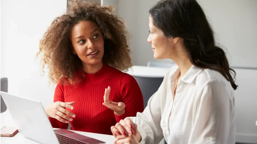 Duas mulheres conversando em ambiente de trabalho.