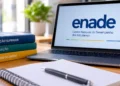 Notebook com identificação do Enade ao lado de livros e materiais de estudo.