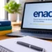 Notebook com identificação do Enade ao lado de livros e materiais de estudo.