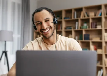 Jovem sorridente assistindo aula em notebook.
