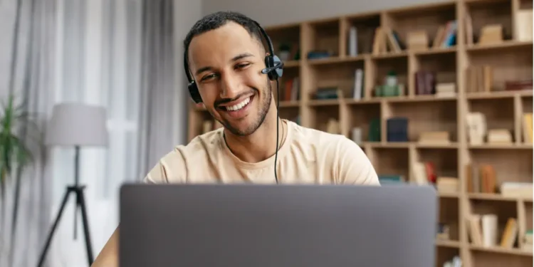 Jovem sorridente assistindo aula em notebook.