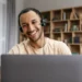 Jovem sorridente assistindo aula em notebook.