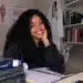 Jovem sorrindo em ambiente de estudos.