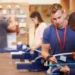 Alunos praticando aula técnica de serralheria com orientação em laboratório.