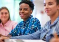 Estudantes sorrindo em sala de aula durante atividade escolar.