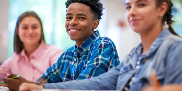 Estudantes sorrindo em sala de aula durante atividade escolar.