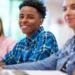 Estudantes sorrindo em sala de aula durante atividade escolar.