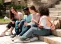 Estudantes universitários conversam em escadaria de campus ao ar livre.