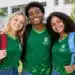 Três estudantes do Ifac sorrindo e abraçados em frente ao campus.